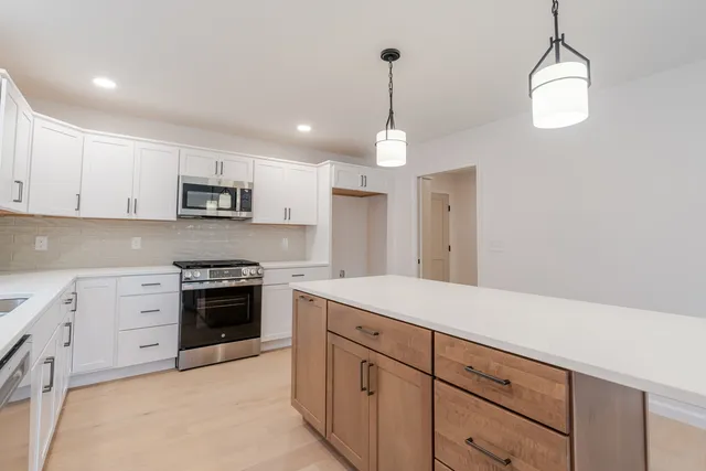 a kitchen with stainless steel appliances granite countertop a sink a stove a refrigerator and cabinets