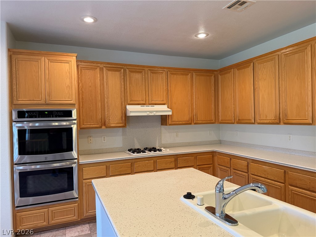 141 Rancho Maria Street Las Vegas, NV 89148 - Photo 12 of 30 Ample wooden cabinetry and integrated stainless steel double ovens frame a functional center island layout.