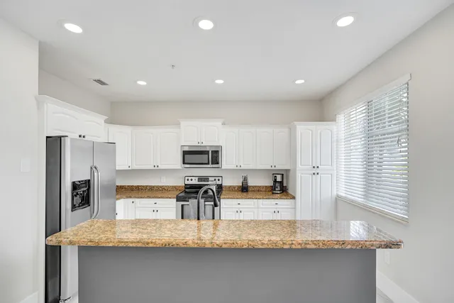 a kitchen with stainless steel appliances granite countertop a sink refrigerator and microwave
