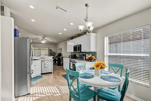 a kitchen with stainless steel appliances kitchen island granite countertop a refrigerator a stove a sink dishwasher a dining table and chairs with wooden floor