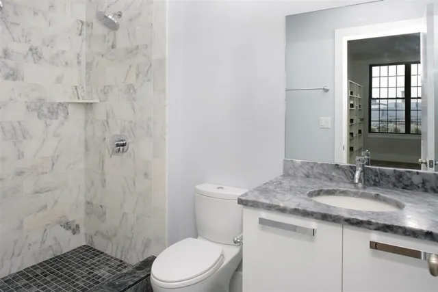 a bathroom with a granite countertop sink toilet and shower