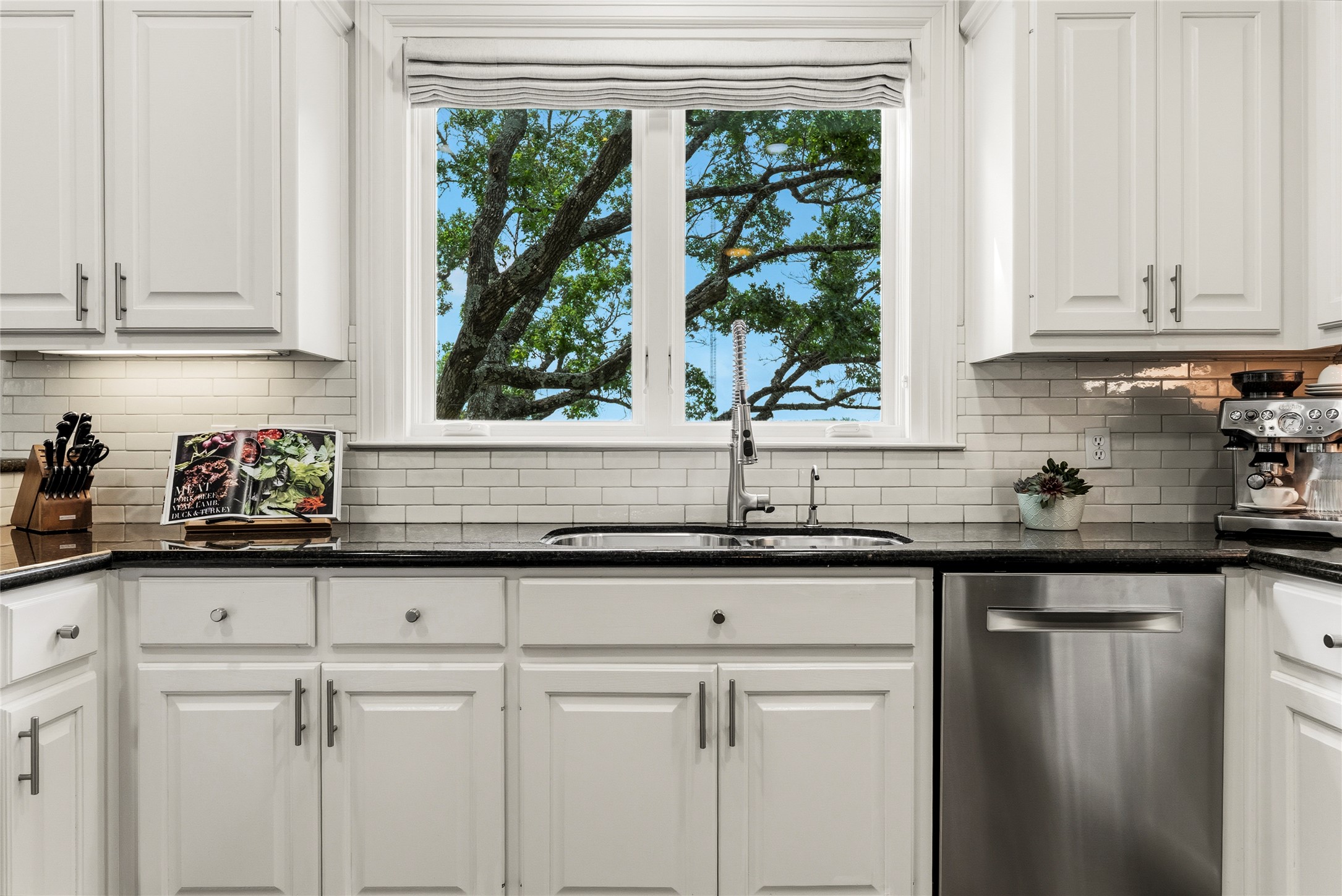 3107 Lookout Lane Austin, TX 78746 - Photo 20 of 39 A well-equipped kitchen features a dual-basin sink beneath a window, framed by extensive white cabinetry and granite countertops.