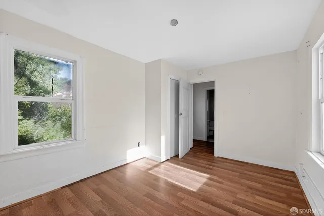 a view of an empty room with wooden floor and a window