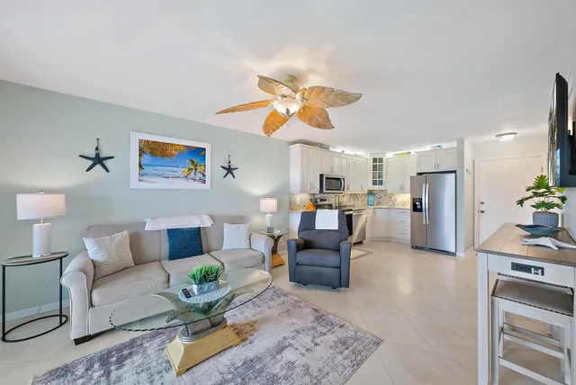 a living room with furniture kitchen view and a chandelier