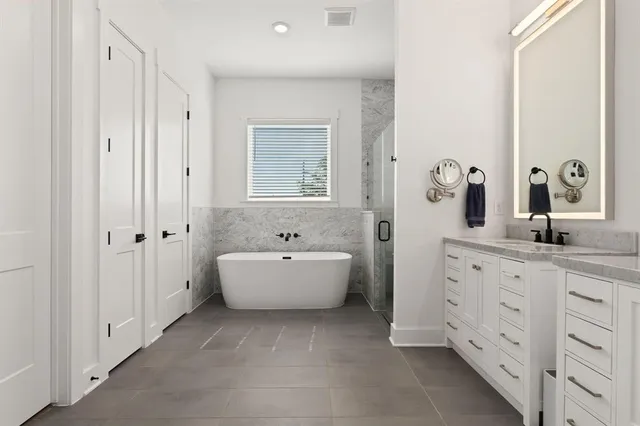 a spacious bathroom with a double vanity sink mirror and bathtub