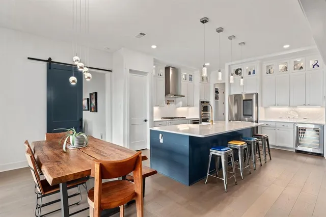 a kitchen with stainless steel appliances kitchen island granite countertop a table chairs sink and cabinets