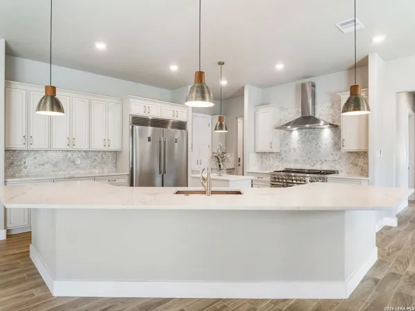 a kitchen with kitchen island a stove a sink a refrigerator and a wooden floor
