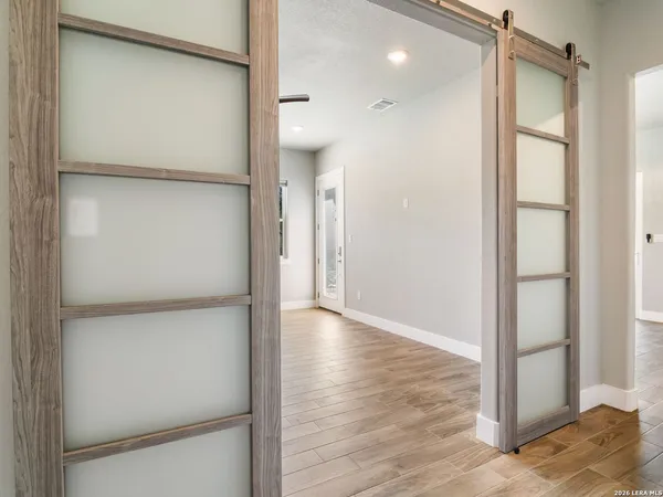 an empty room with wooden floor chandelier and windows