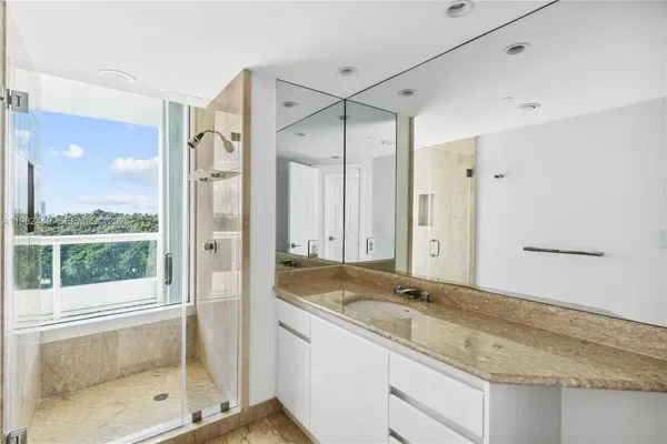 a bathroom with a granite countertop sink mirror and shower
