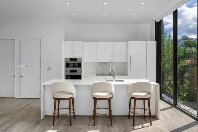 a kitchen with stainless steel appliances a table and chairs in it