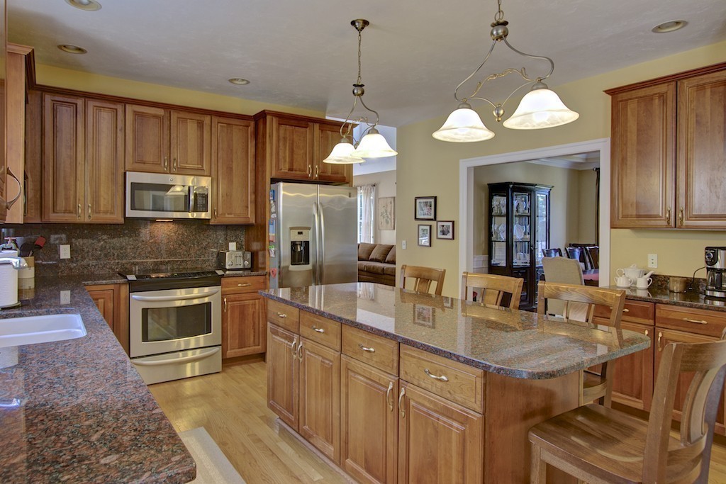 21 Falcon Ridge Drive Hopkinton, MA 01748 - Photo 3 of 30 a kitchen with kitchen island granite countertop a stove a sink a refrigerator dining table and chairs