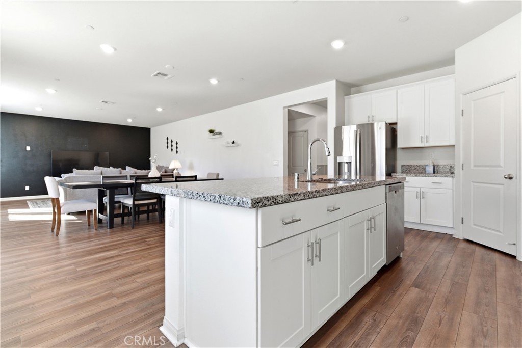 15594 Raptor Road Moreno Valley, CA 92551 - Photo 18 of 53 a kitchen with stainless steel appliances kitchen island granite countertop a stove a sink a refrigerator and white cabinets with wooden floor