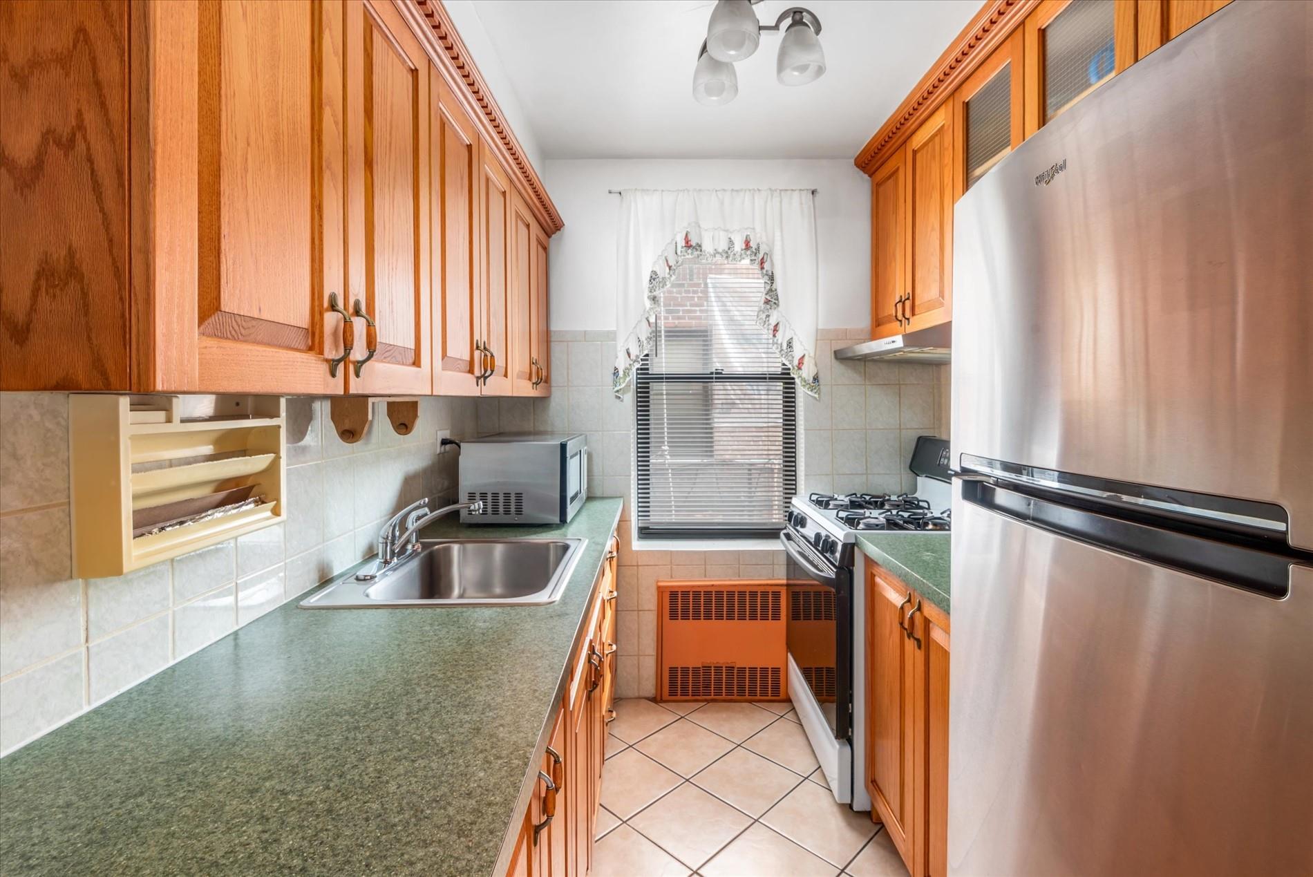83-75 Woodhaven Boulevard, Unit 1E Queens, NY 11421 - Photo 7 of 15 a kitchen with stainless steel appliances granite countertop a sink a stove and a refrigerator