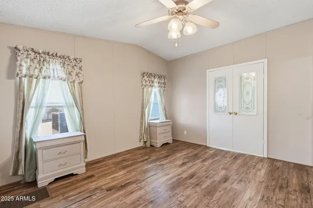 a view of empty room with wooden floor and fan