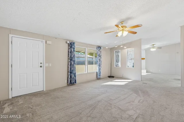 an empty room with windows and a chandelier fan