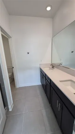 a spacious bathroom with a double vanity sink a toilet and a mirror