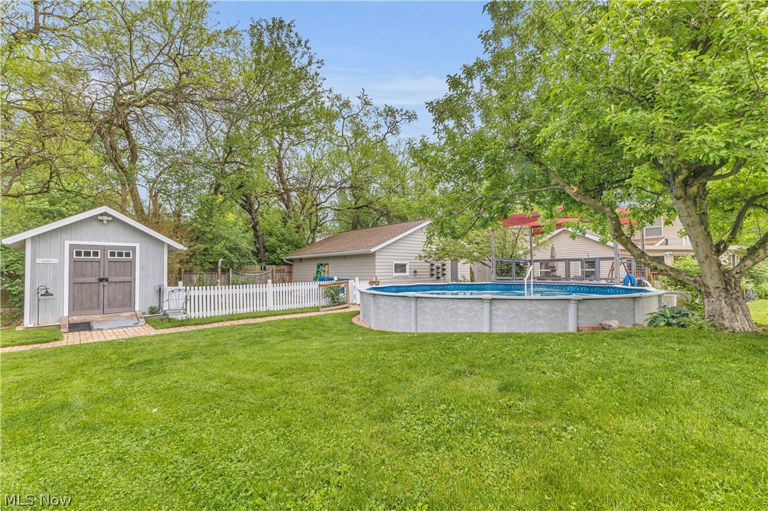 8704 Columbia Road Olmsted Falls, OH 44138 - Photo 28 of 34 Expansive backyard featuring a manicured lawn, a detached storage shed with double doors, a white picket fence, and an above-ground pool