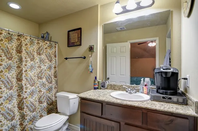 a bathroom with a granite countertop toilet sink and mirror