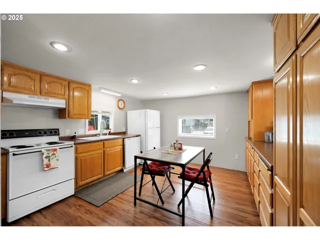 a kitchen with stainless steel appliances kitchen island granite countertop a refrigerator a stove a microwave oven with white cabinets and wooden floor