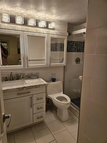 a bathroom with a granite countertop toilet a sink and a mirror