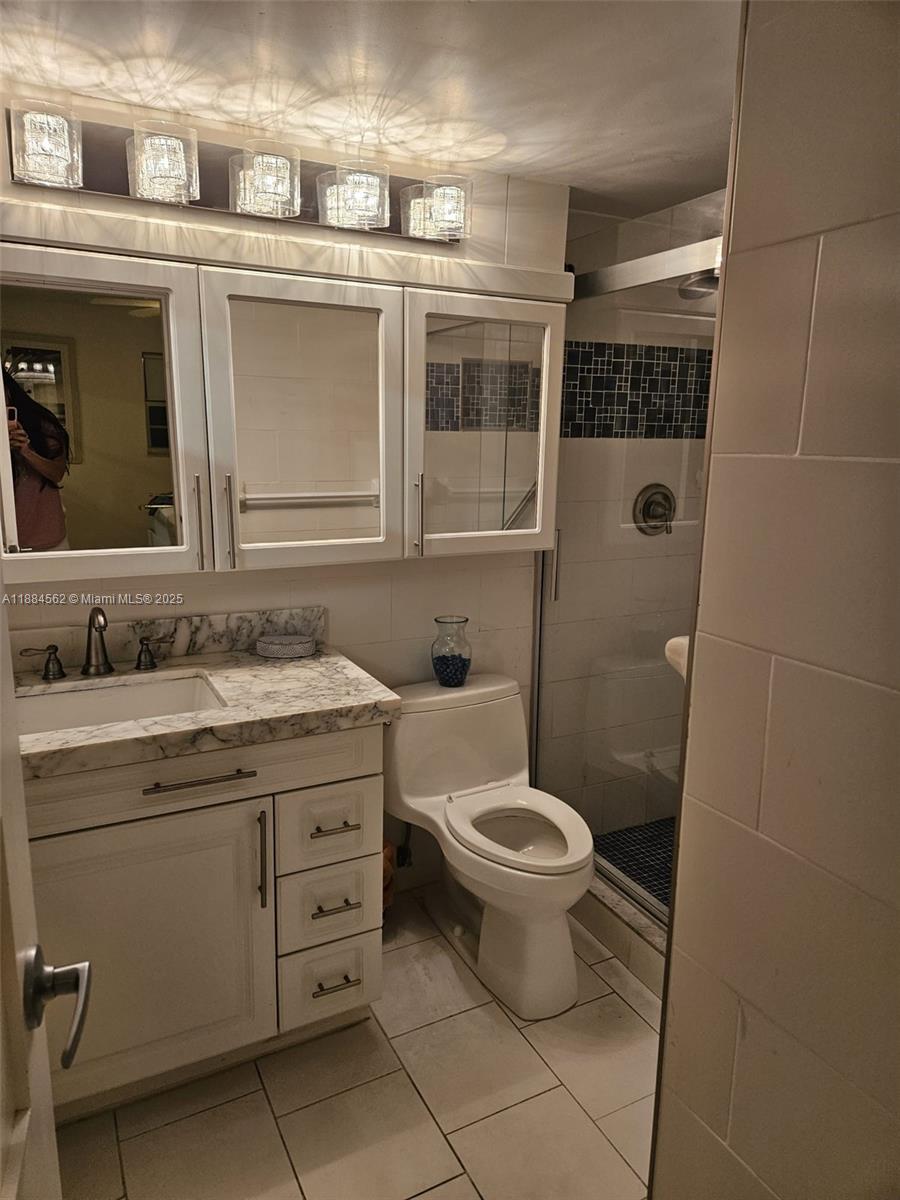 8425 Harding Avenue, Unit 1 Miami Beach, FL 33141 - Photo 8 of 16 a bathroom with a granite countertop toilet a sink and a mirror
