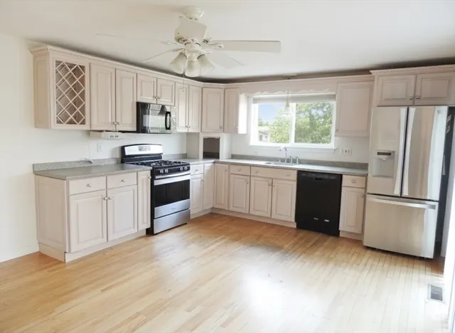 a kitchen with stainless steel appliances white cabinets a sink a stove a refrigerator and microwave