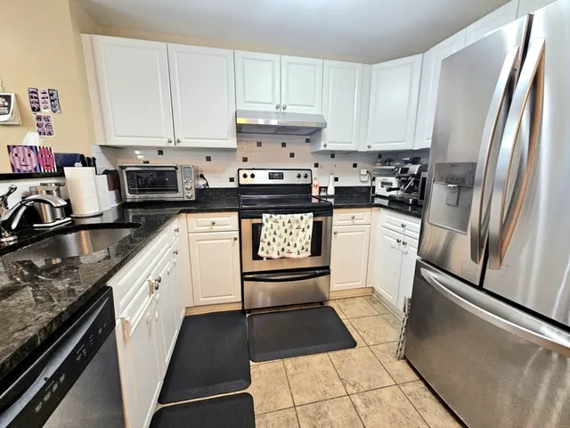 a kitchen with granite countertop a refrigerator stove and sink