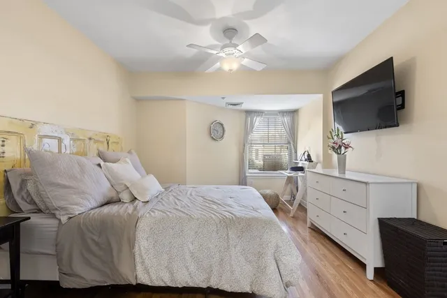 a bedroom with a large bed and a flat tv screen on dresser