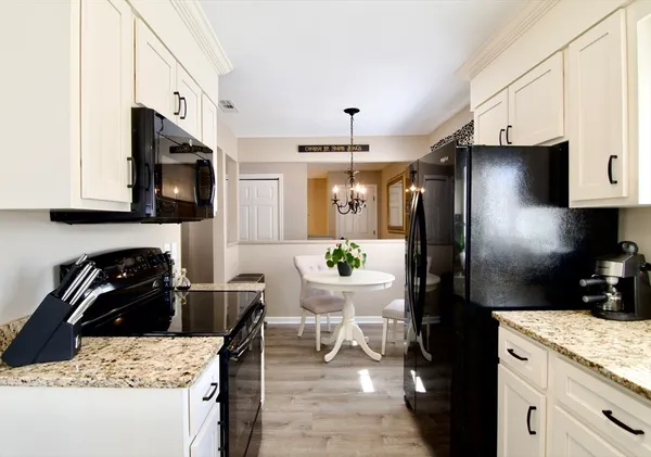 a kitchen with granite countertop white cabinets and refrigerator