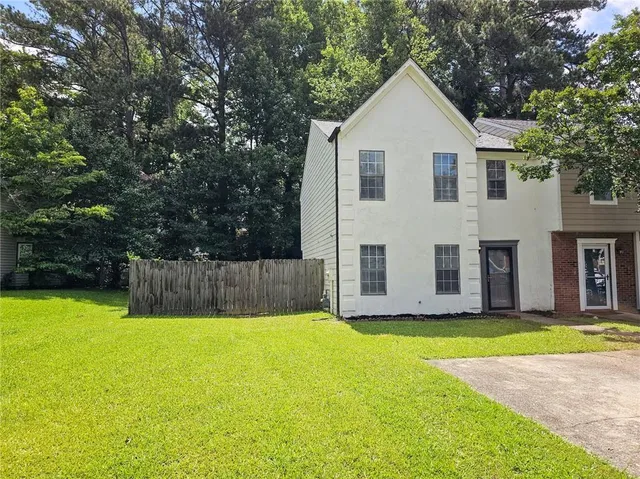 a view of a house with a yard and large tree