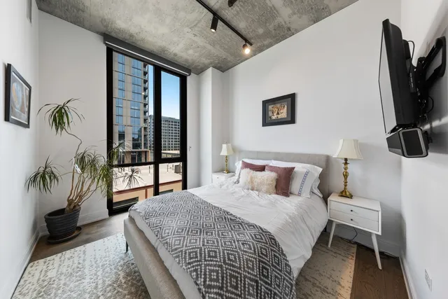 a bedroom with a bed a couch and a flat tv screen on the dresser