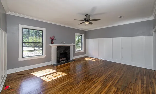 a view of an empty room with wooden floor fireplace and a window