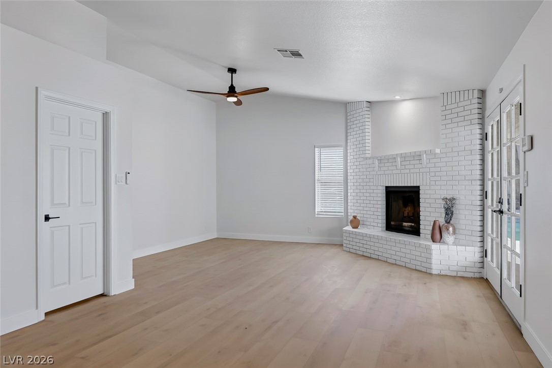 434 Crestway Road Henderson, NV 89015 - Photo 20 of 46 Unfurnished living room with a brick fireplace, light wood-style floors, and a ceiling fan