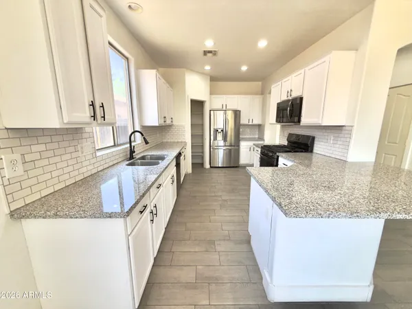 a large kitchen with kitchen island granite countertop a large counter top stainless steel appliances and cabinets