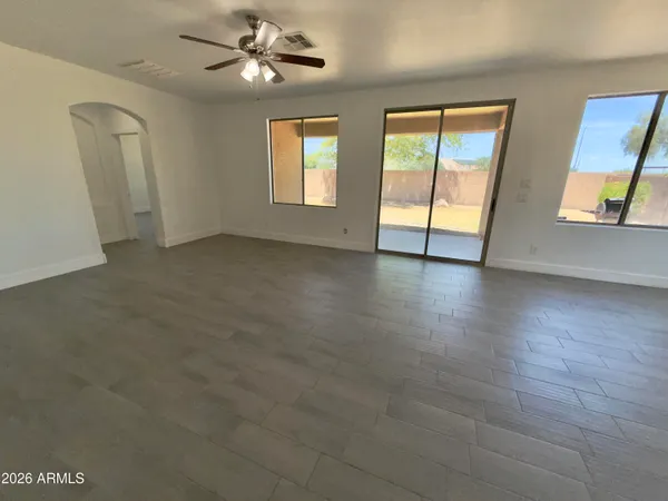 an empty room with wooden floor fan and windows