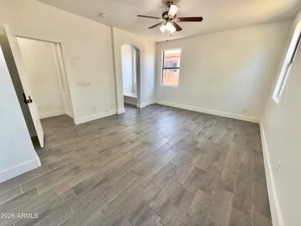 an empty room with wooden floor and a ceiling fan