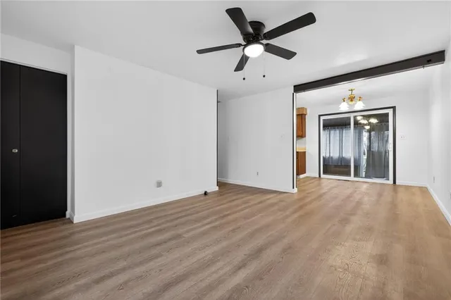an empty room with wooden floor and ceiling fan