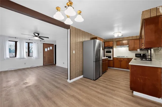 a kitchen with stainless steel appliances granite countertop a refrigerator a sink dishwasher a stove and a dining table with wooden floor