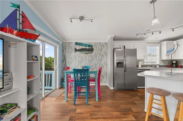 a kitchen with stainless steel appliances granite countertop a dining table chairs refrigerator and sink