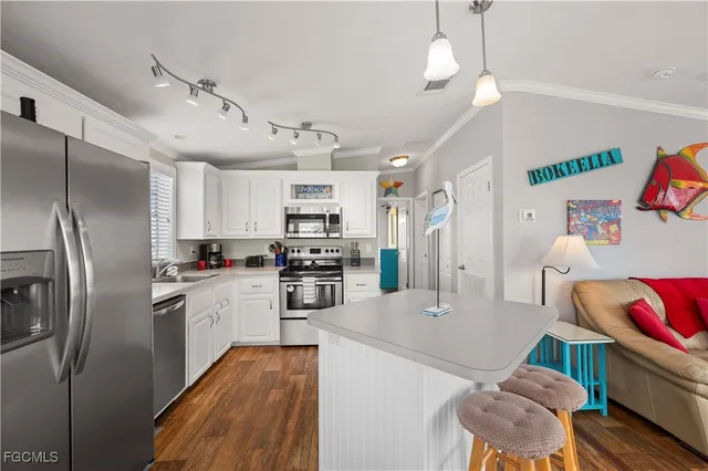 a kitchen with stainless steel appliances kitchen island granite countertop a refrigerator a stove top oven a sink dishwasher and a refrigerator with wooden floor