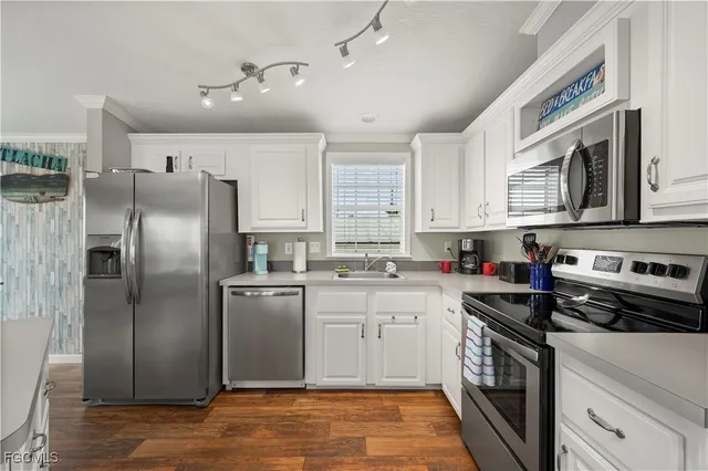 a kitchen with stainless steel appliances granite countertop a stove top oven a refrigerator a sink and dishwasher with white cabinets