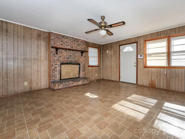 an empty room with windows and fireplace