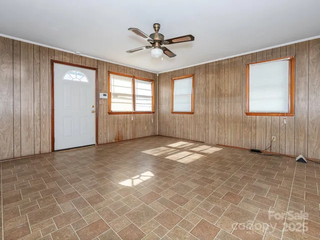 an empty room with windows and ceiling fan