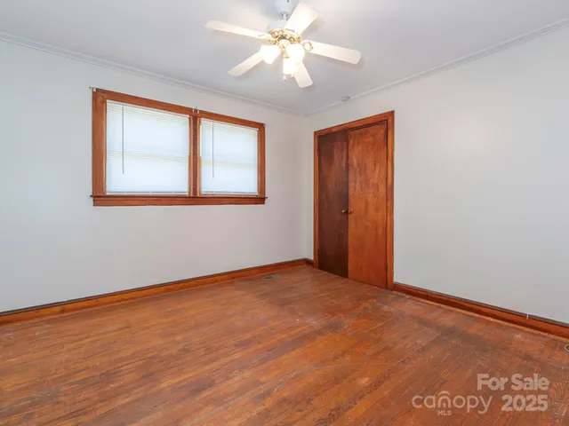 a view of an empty room with window and a chandelier fan