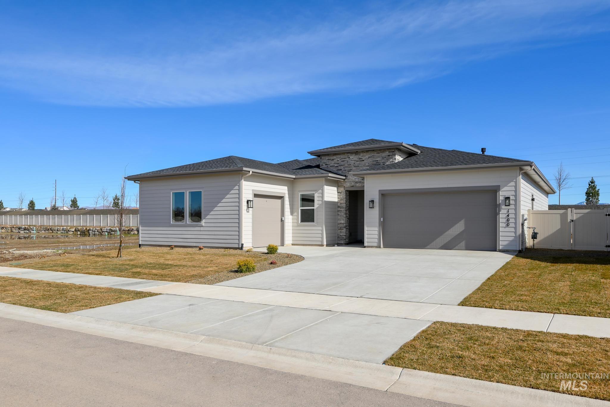 8459 South Country Wind Avenue Meridian, ID 83642 - Photo 2 of 11 Prairie-style home featuring an attached garage, driveway, a shingled roof, and a gate