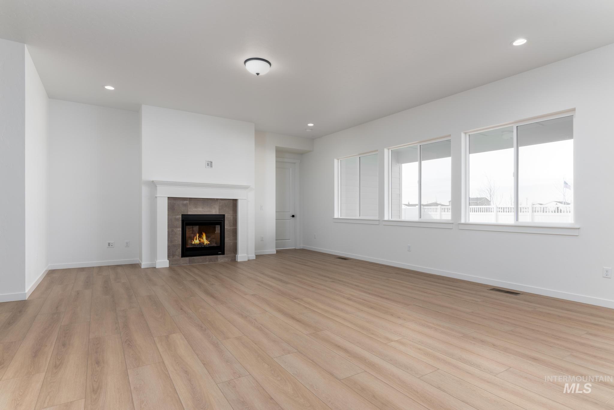 8459 South Country Wind Avenue Meridian, ID 83642 - Photo 3 of 11 Unfurnished living room with light wood finished floors, a fireplace, and recessed lighting