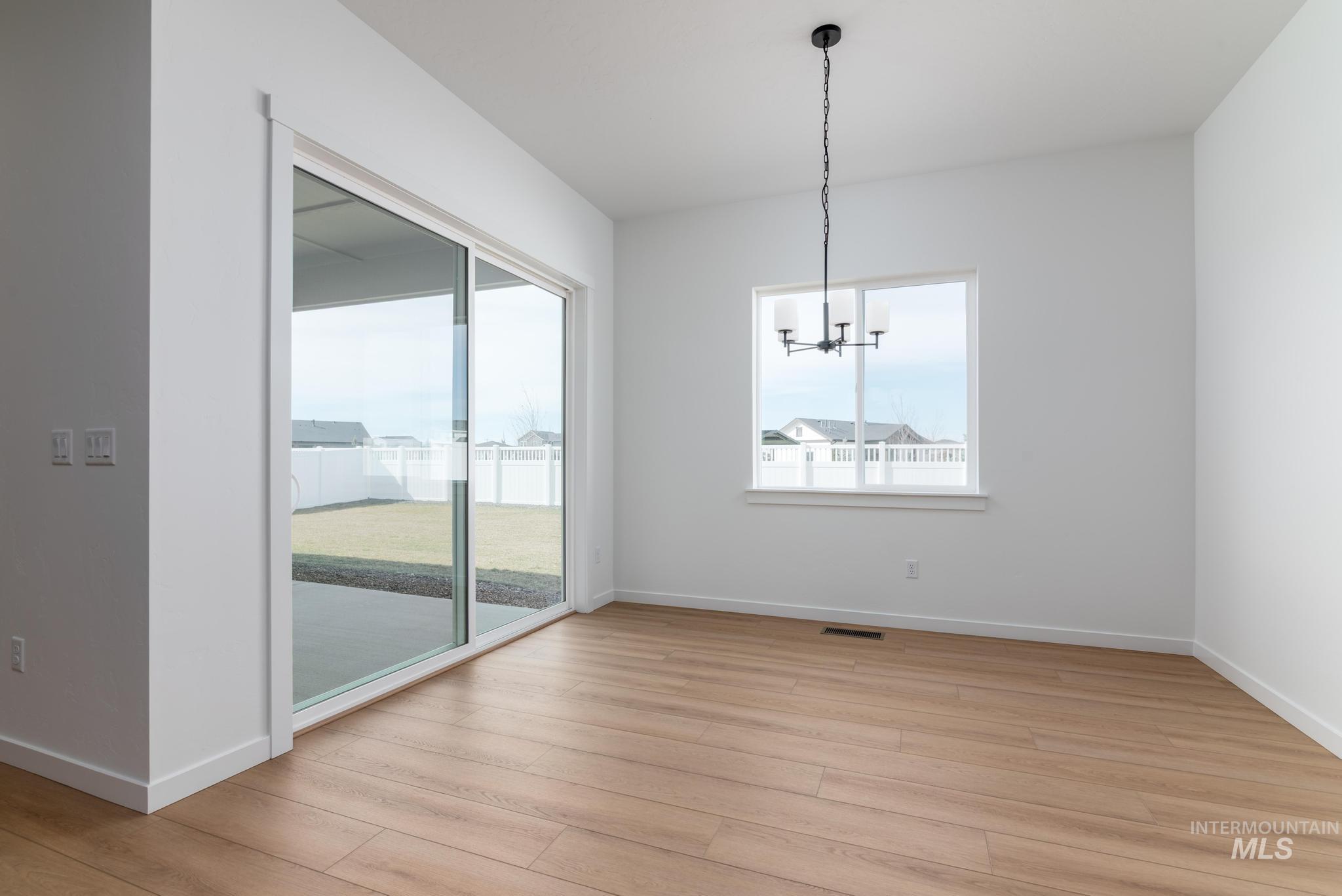 8459 South Country Wind Avenue Meridian, ID 83642 - Photo 7 of 11 Unfurnished dining area with light wood-style floors and suspended lighting
