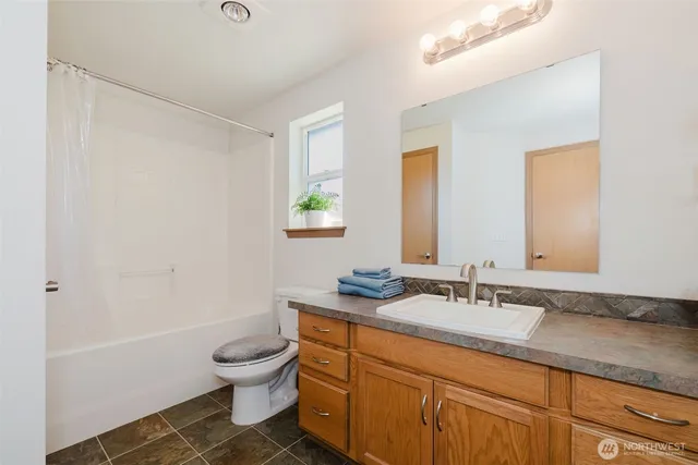 a bathroom with a granite countertop sink a toilet and a mirror