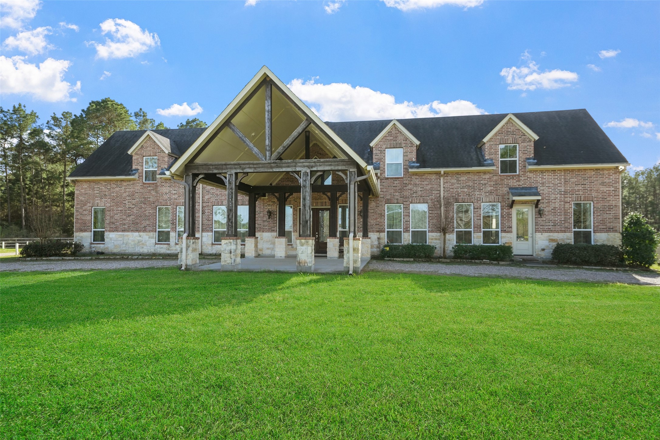 26250 A Riley Road Waller, TX 77484 - Photo 29 of 50 Grand front elevation with soaring covered entry, rustic wood beams, and brick/stone detailing; double leaded-glass doors create a striking welcome.