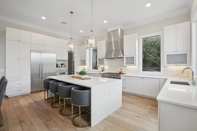 a kitchen with stainless steel appliances granite countertop a sink a stove a refrigerator and island with wooden floor